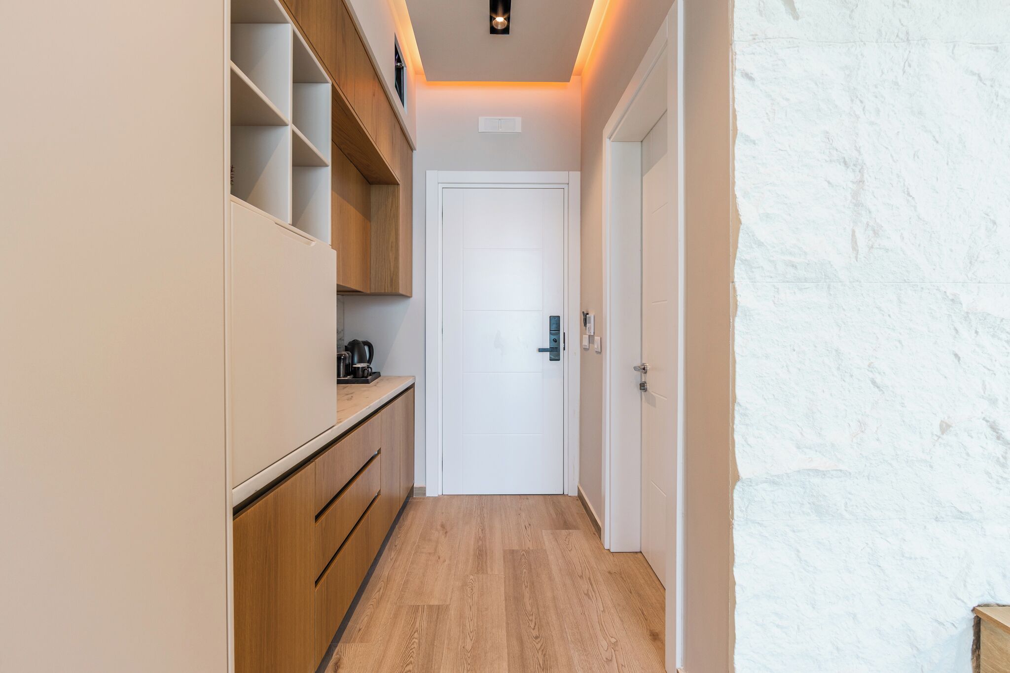 A narrow hallway with wooden cabinets and a white door at the end.
