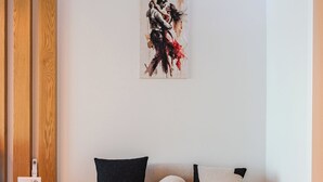 Una sala de estar moderna con un sofá redondo, una mesita de madera y una obra de arte colgada en la pared.