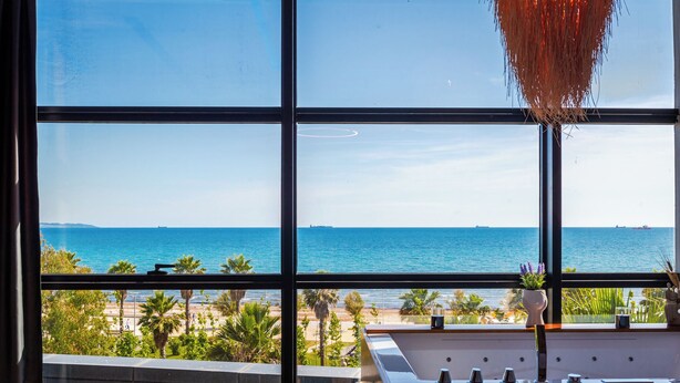 Una habitación con un amplio ventanal con vistas a una playa y al mar.