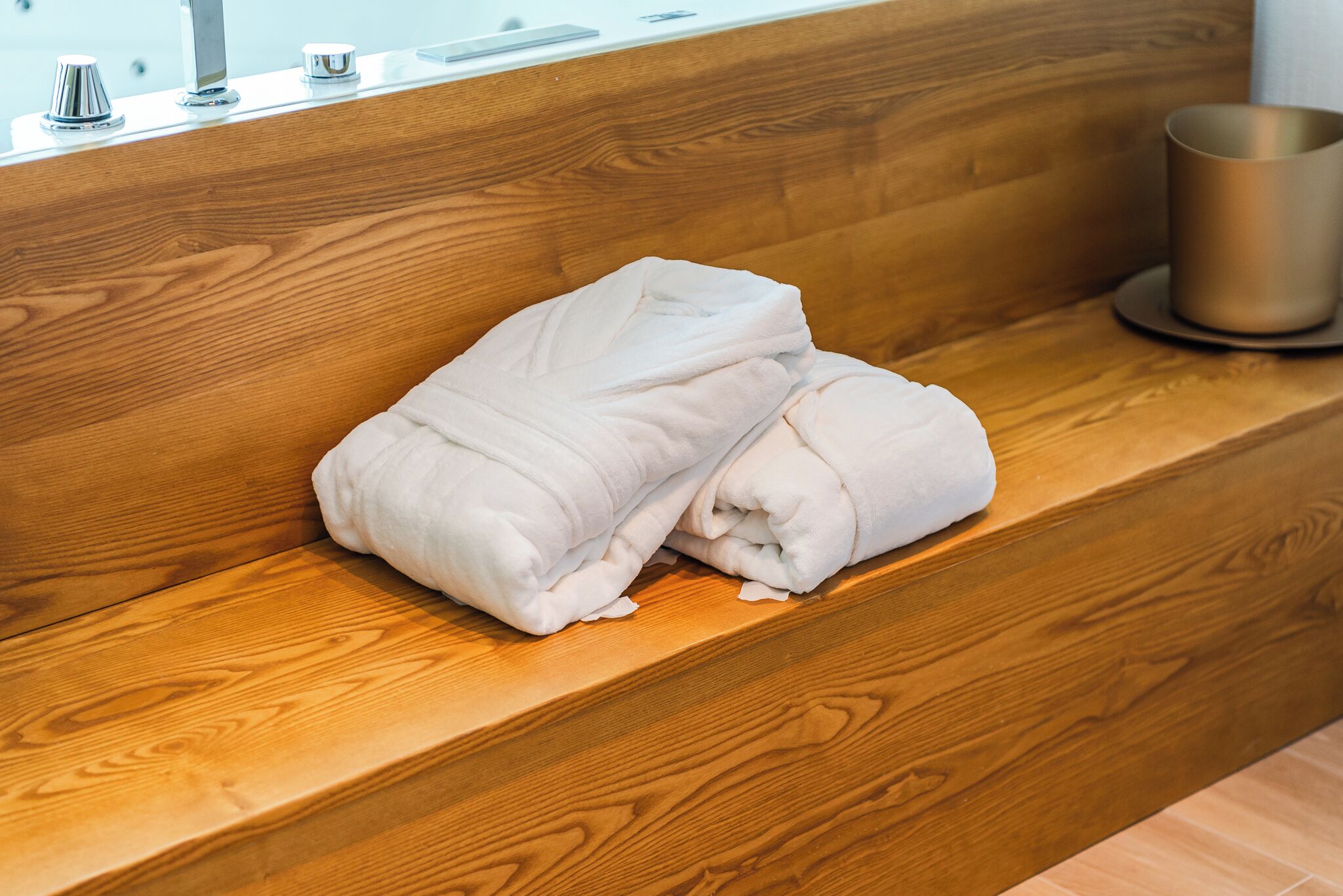 Een houten bank met opgevouwen handdoeken en een metalen bak.