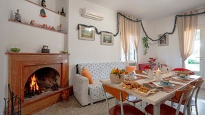 A cozy living room with a fireplace, a dining table set for a meal, and a sofa. - Oasi Villa Anthea Apartment with Exclusive-Use Pool, Wi-Fi, and Air Conditioning (Monopoli)