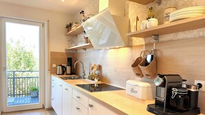 Una cucina moderna con un'ampia finestra, mobili in legno, una macchina per il caffè e diversi utensili da cucina.