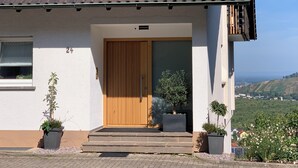 Una casa moderna con una porta in legno, piante in vaso e vista sul paesaggio.