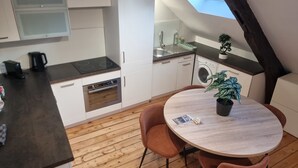 Een moderne keuken met witte kasten, een ingebouwde oven, een wasmachine en een dakraam.