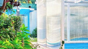 A pool area with a covered patio, surrounded by lush greenery and a view of a hilly landscape. - Şilede doğa içinde denize yakın kapalı ısıtmalı havuzlu şömineli barbekülü villa (İmrenli)