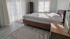 A bedroom with a bed, a bedside table, a wardrobe, and a window with sheer curtains. - Şilede doğa içinde denize yakın kapalı ısıtmalı havuzlu şömineli barbekülü villa (İmrenli)
