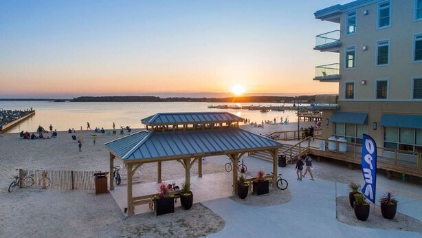 Un hotel frente a la playa con un pabellón techado, un muelle y vistas al atardecer.