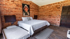 A room with a brick wall, a bed with two pillows, a TV, and a door. - Anana Casa SK Villa With Garden Family-friendl (Chapala)