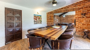 A long wooden dining table with chairs, a brick wall, and a white brick wall with a mural. - Anana Casa SK Villa With Garden Family-friendl (Chapala)