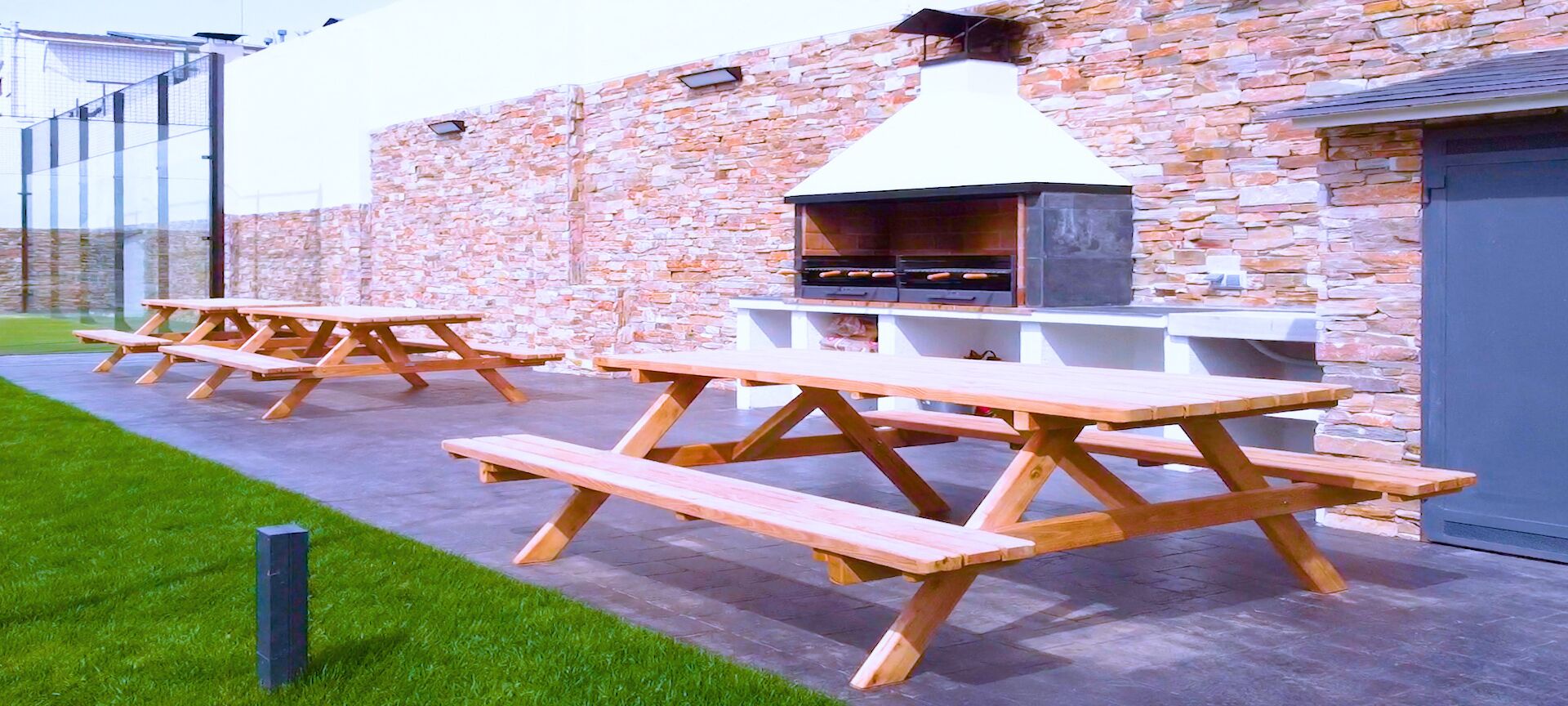 Eine Außenpatio-Terrasse mit Picknicktischen und einer Steinmauer.