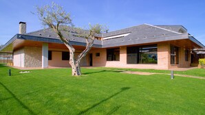 A modern house with a sloped roof, large windows, and a well-maintained lawn. - Casa de Vacaciones con pádel en Montseny by Can Forcadell (Breda)