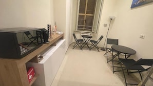 A compact kitchen with a dining area, a window with blinds, and a small table with chairs. - Rome Jubilee Stays 2 (Rome)