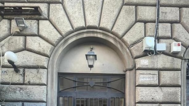 A building entrance with a stone facade, a metal gate, and a street lamp above. - Rome Jubilee Stays 2 (Rome)