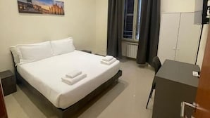 A hotel room with a bed, a desk, a chair, a painting, and a window with curtains. - Rome Jubilee Stays 2 (Rome)