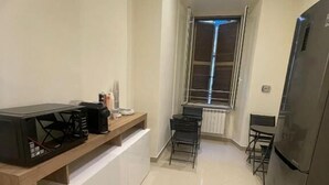 A compact kitchen with a wooden countertop, a built-in microwave, a refrigerator, and a window with blinds. - Rome Jubilee Stays 2 (Rome)