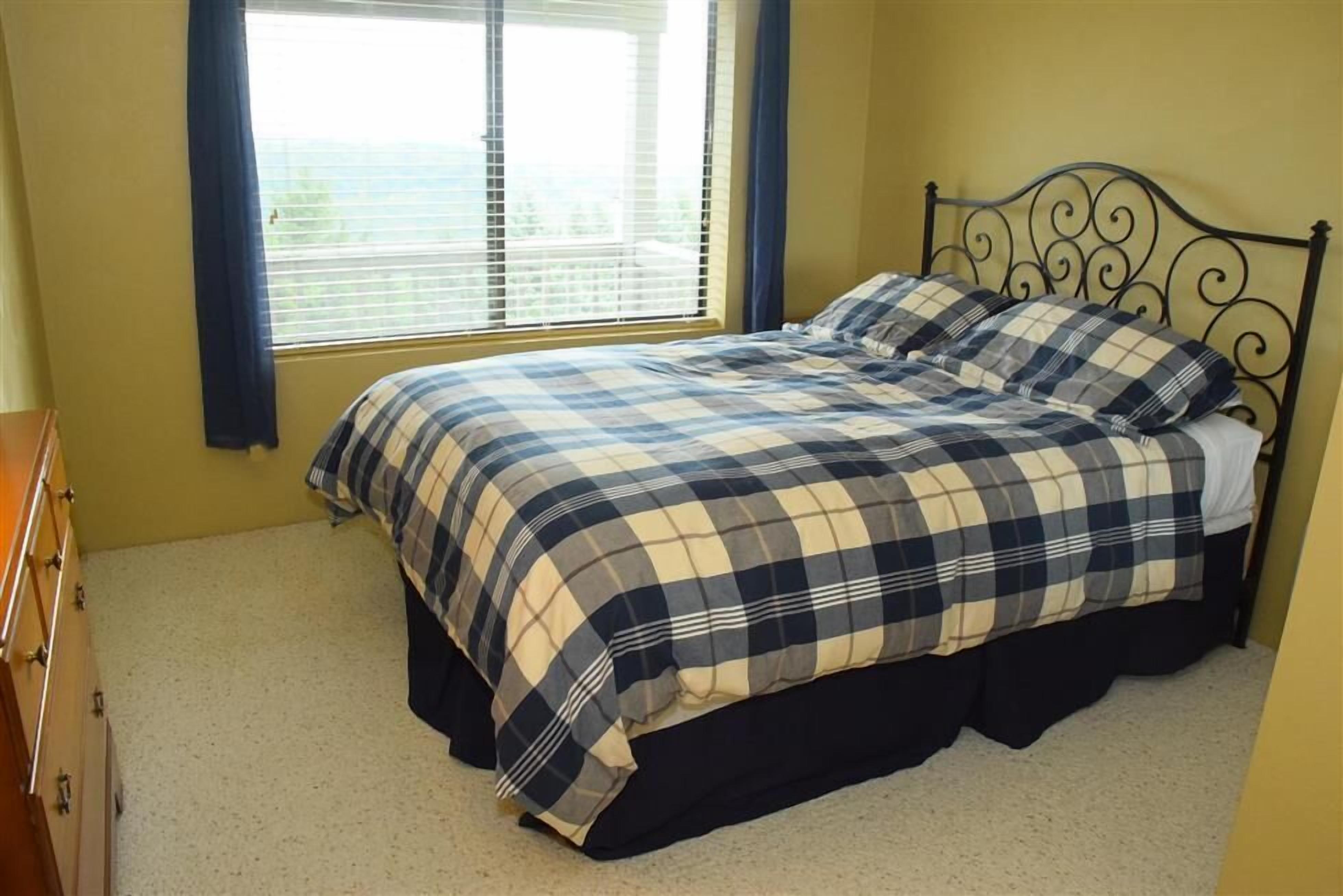 Une chambre à coucher avec un lit, une commode et une fenêtre avec des rideaux.