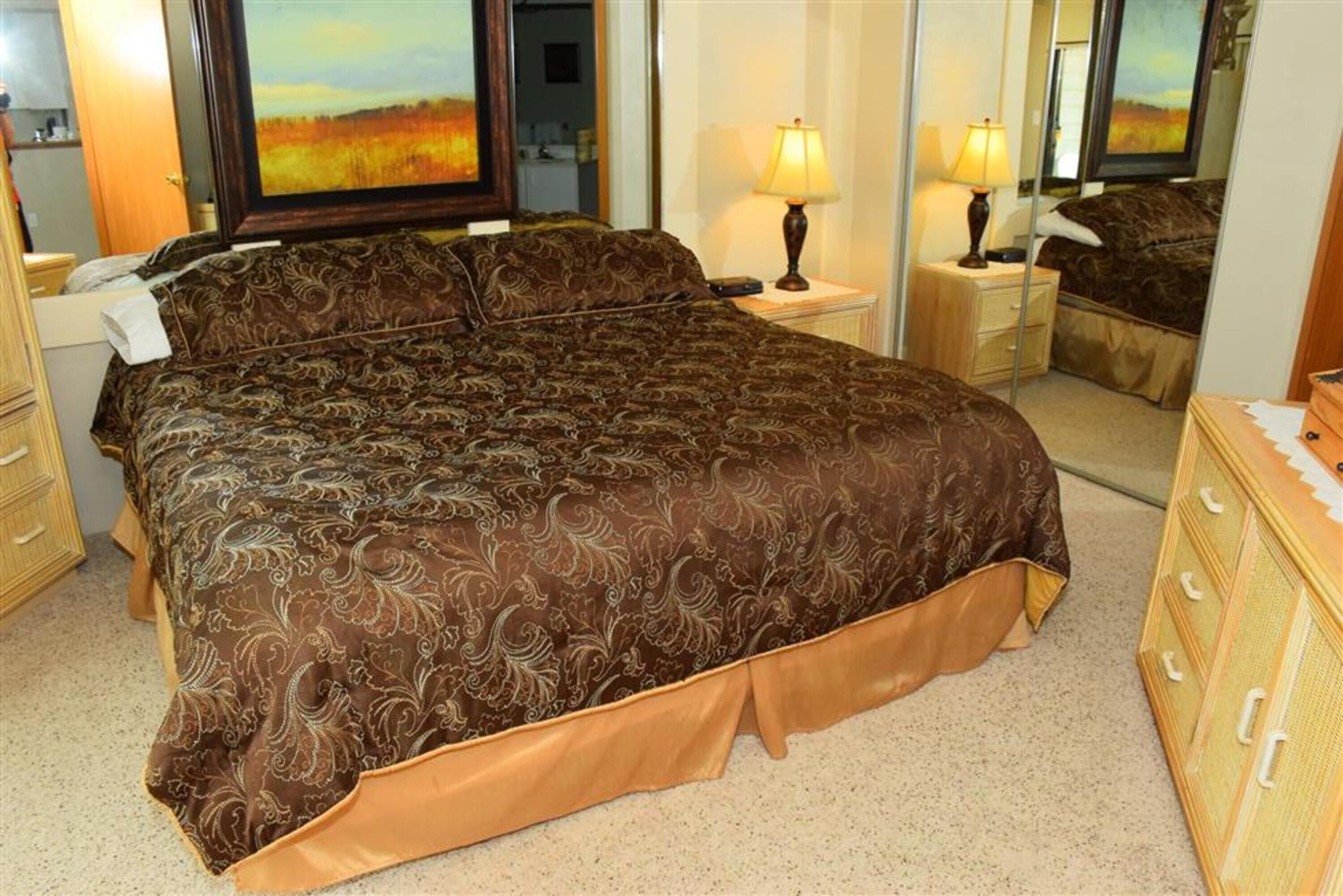 Ein Schlafzimmer mit einem großen Bett, zwei Nachttischen, einem Spiegel und einer Kommode.