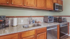 Cucina con mobili in legno, lavello in acciaio inossidabile, forno a microonde, tostapane e forno.