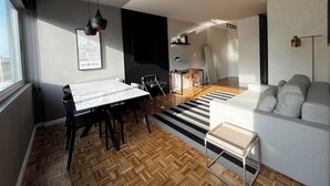 Ett modernt vardagsrum med en soffa, ett matbord med stolar, en svartvit randig matta och en svartvit mönstrad vägg.
