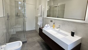 Un baño moderno con ducha de vidrio, tocador doble y espejo grande.