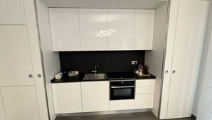 Una cocina compacta con armarios blancos, una encimera negra y un horno empotrado.