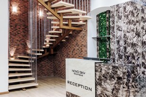 Un interior moderno con una escalera espiral de madera, una recepción y una pared con diseño de hojas verdes.