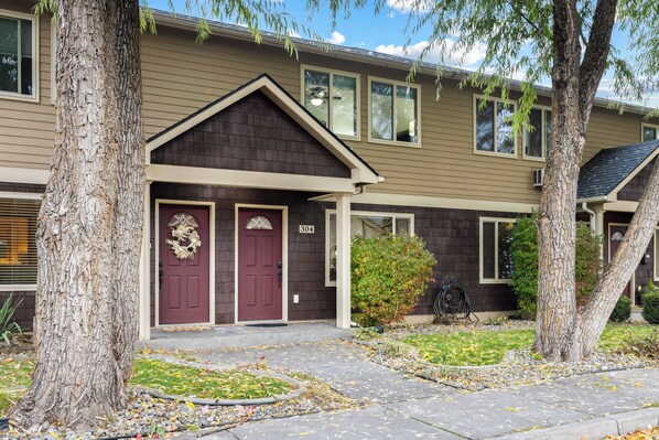 A two-story building with a dark brown facade, a red door, and a number 304 sign. - Peaceful Downtown Gem with Fireplace & Patio (Coeur d'Alene)
