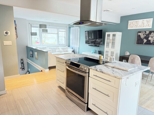A modern kitchen with a built-in oven, a microwave, and a stovetop. There is a dining area with a table and chairs. - 3-bedroom 2-bath house in Norwalk with in-law suite, pool, BBQ (Norwalk)