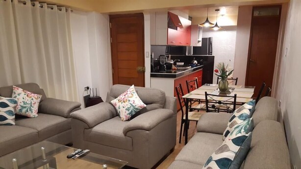 A living room with three sofas, a glass coffee table, and a dining area with a table and chairs. - Rosaelena b&b tours and experiences with transportation included 7persons (Cusco)
