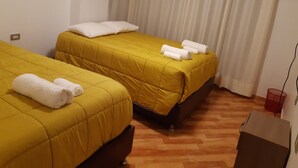 A hotel room with two beds, each with a yellow bedspread and white pillows, and a red trash bin. - Rosaelena b&b tours and experiences with transportation included 7persons (Cusco)