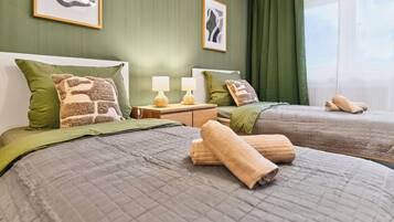 A hotel room with two beds, green walls, and artwork.