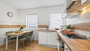 A modern kitchen with white cabinets, a wooden countertop, and a dining area with a table and chairs. - Tina in Buchen (Buchen)