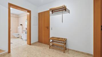 A hallway with a wooden door, a wooden shelf, and a hanging rack.