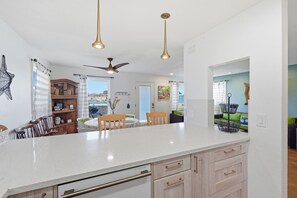 Une cuisine moderne avec un plan de travail blanc, des armoires en bois et un ventilateur de plafond.