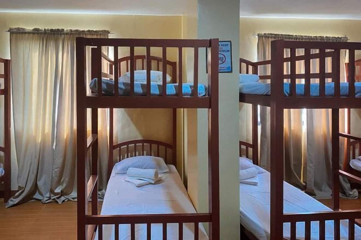 A room with two bunk beds, a curtain, and a sign on the wall.