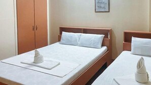 Et hotelværelse med to senge, trægavle, hvide hørklæder og et indramet citat på væggen.