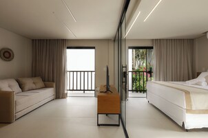 Una habitación de hotel moderna con sofá, cama, televisión y balcón con vistas.