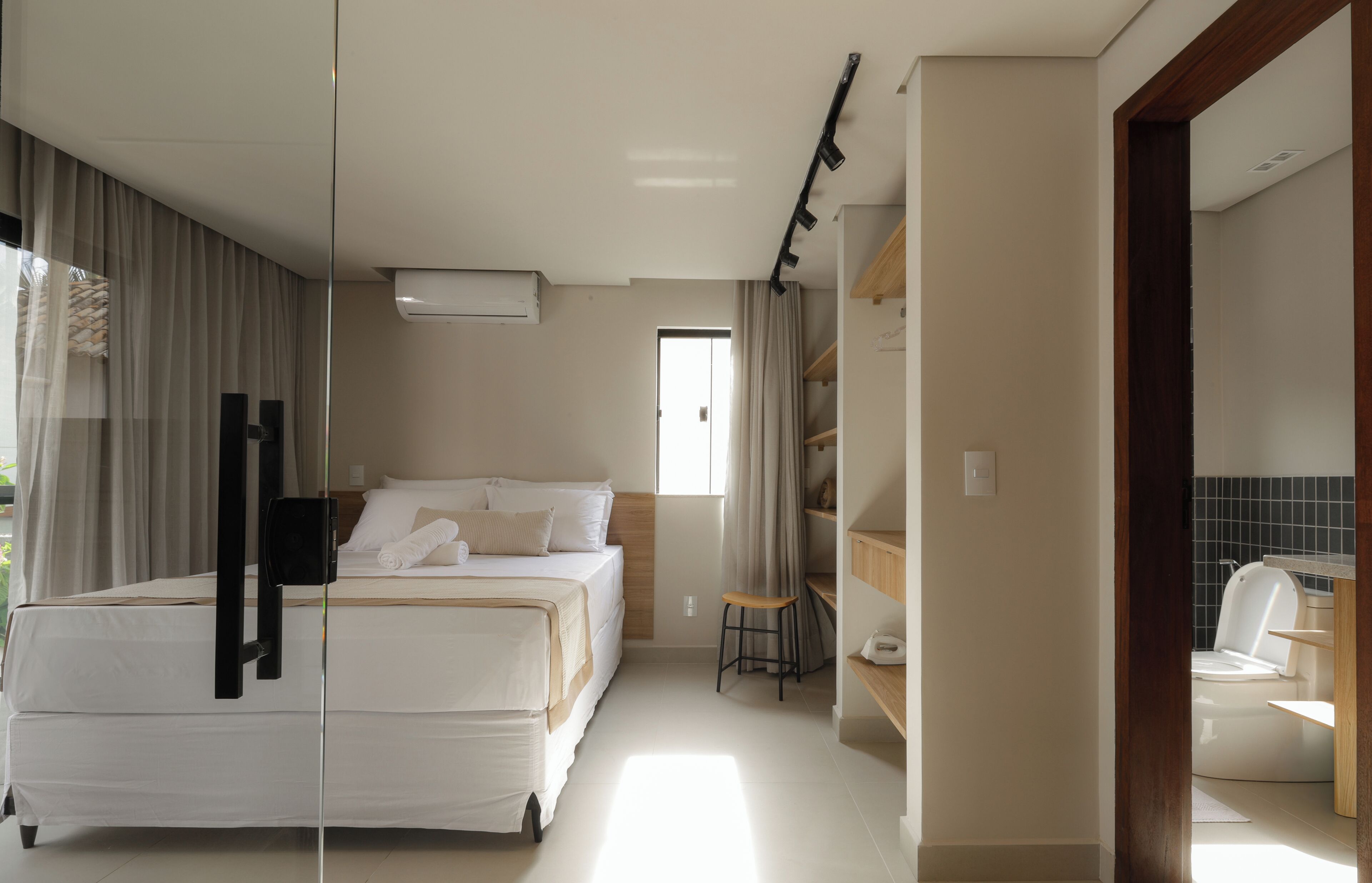 A bedroom with a bed, a desk, and a bathroom visible through an open door.