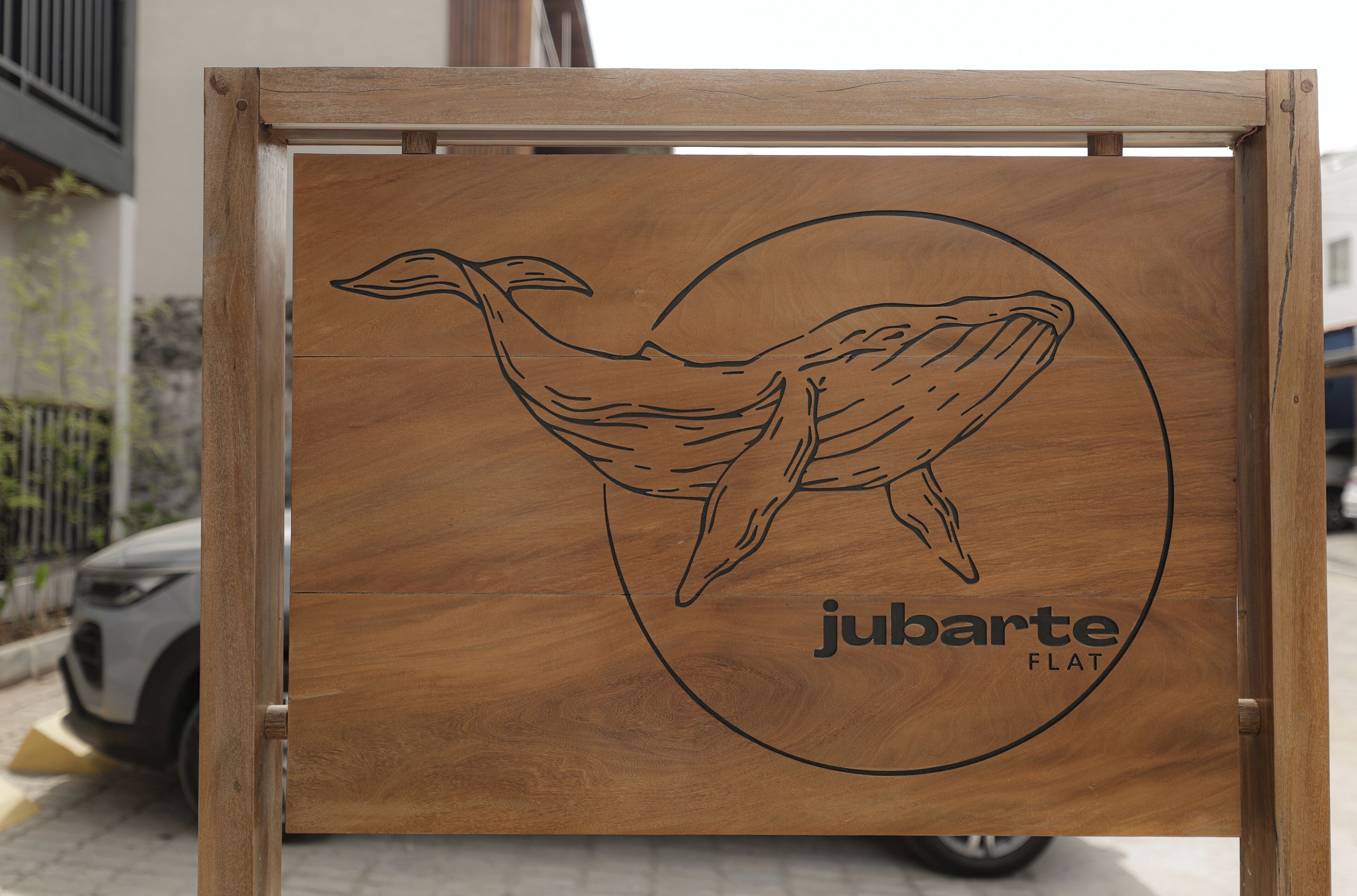Un panel de madera con una ilustración de un ave y el texto 'jubarte FLAT'.