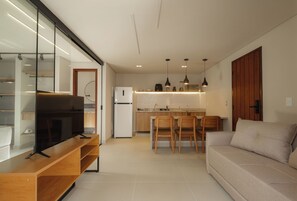 Una cocina moderna con comedor, un sofá y un televisor sobre un soporte de madera.