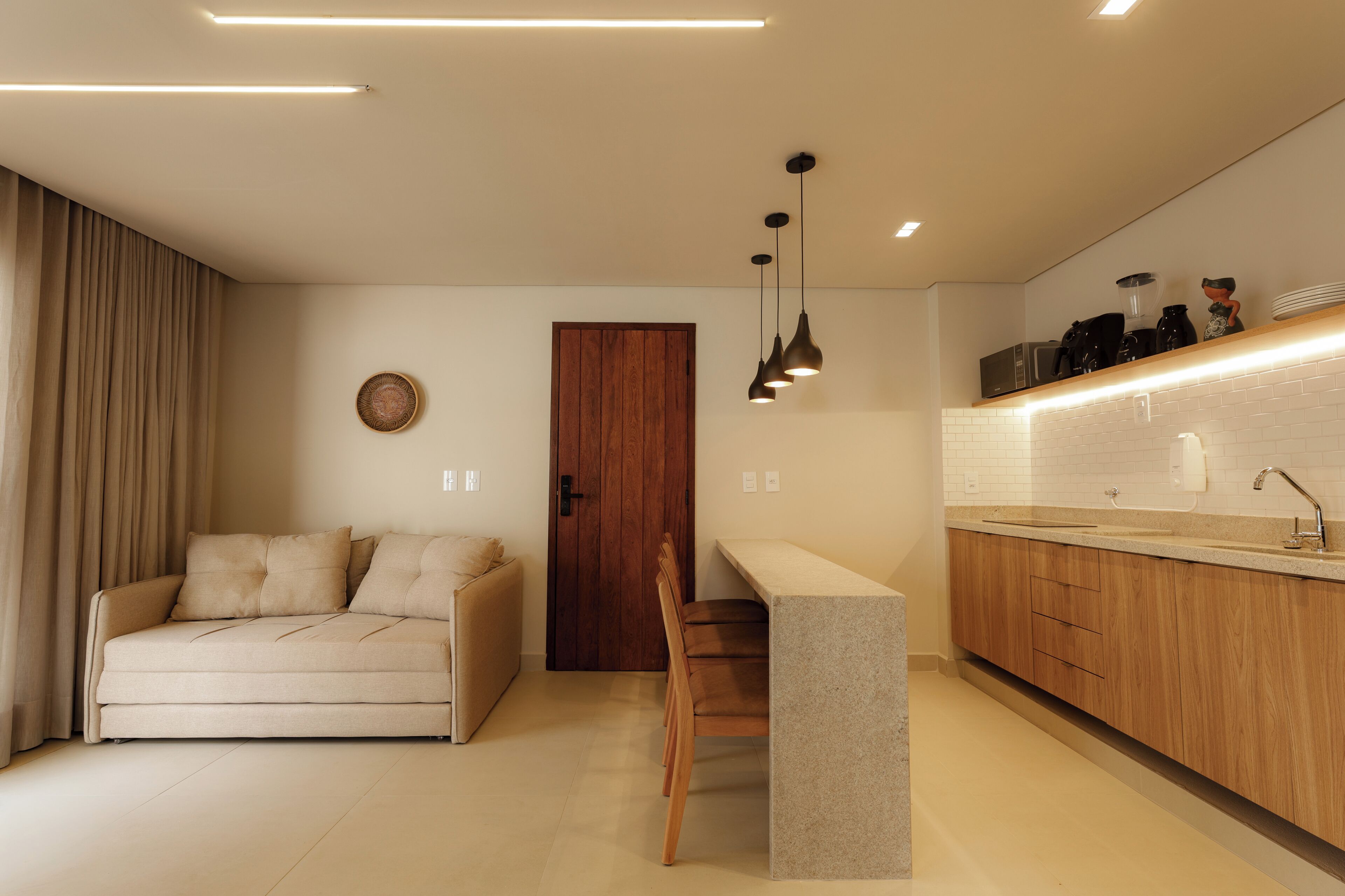 Uma cozinha moderna com bancada de madeira, um banco embutido e iluminação pendente.