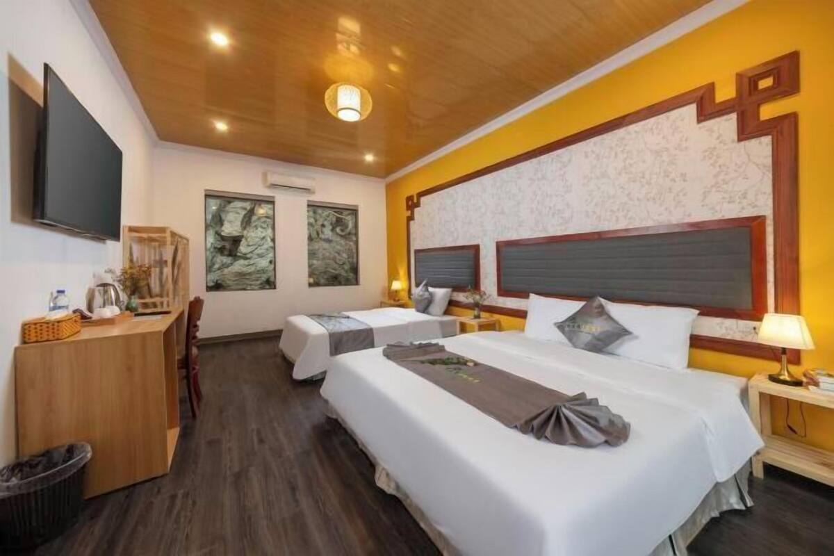 A hotel room with two beds, a desk, a TV, and artwork on the walls.
