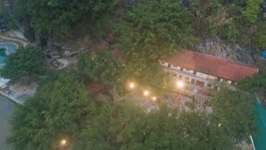 A building surrounded by dense forest, with a visible swimming pool and a red-roofed structure. - Trang An Ecorest Resort & Spa (Hoa Lu District)