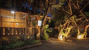 A rustic wooden building with a balcony, surrounded by dense vegetation and illuminated by string lights. - Trang An Ecorest Resort & Spa (Hoa Lu District)