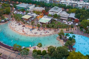 An aerial view of a beach resort with multiple pools, a sandy beach, and surrounding buildings. - Saphira Edge Art Deco Elegance in Brisbanes Heart (Brisbane)