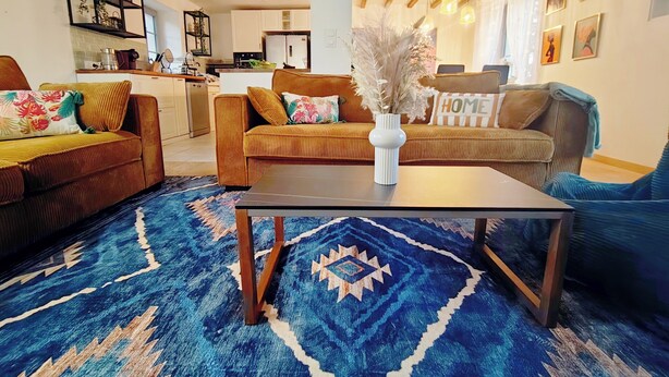 Una sala de estar con un tapete azul estampado, una mesa de centro y dos sofás con almohadones decorativos.