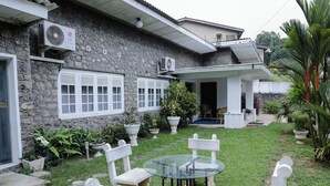 A stone house with a patio, a glass table, and white chairs. - Cozy Nest Kandy Villa (Kandy)