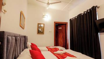 Una habitación de hotel con una cama, un ventilador de techo, un cuadro enmarcado y una puerta.
