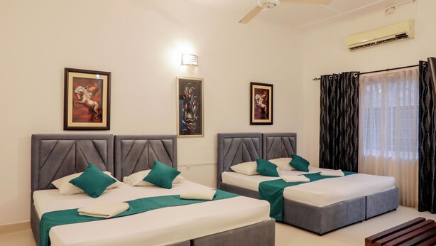 A hotel room with two beds, a ceiling fan, an air conditioning unit, and artwork on the walls. - Cozy Nest Kandy Villa (Kandy)