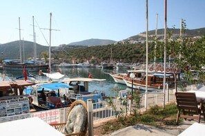 A marina with boats docked, a rocky foreground, and a hilly landscape in the background. - Secluded Villa with Large Private Pool & Beautiful Gardens | Walk to Kalkan Town (Kalkan)